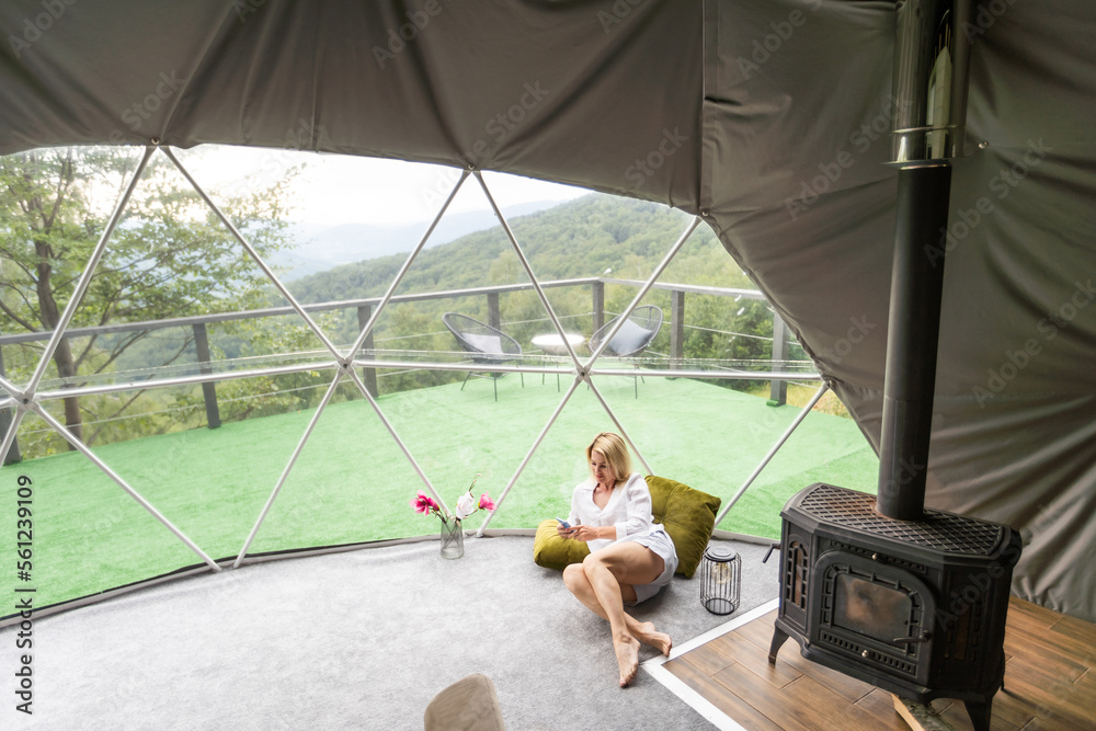A woman sits in a geo dome glamping tent, looks at the nature. A woman sits in a geo dome glamping tent, looks at the nature.