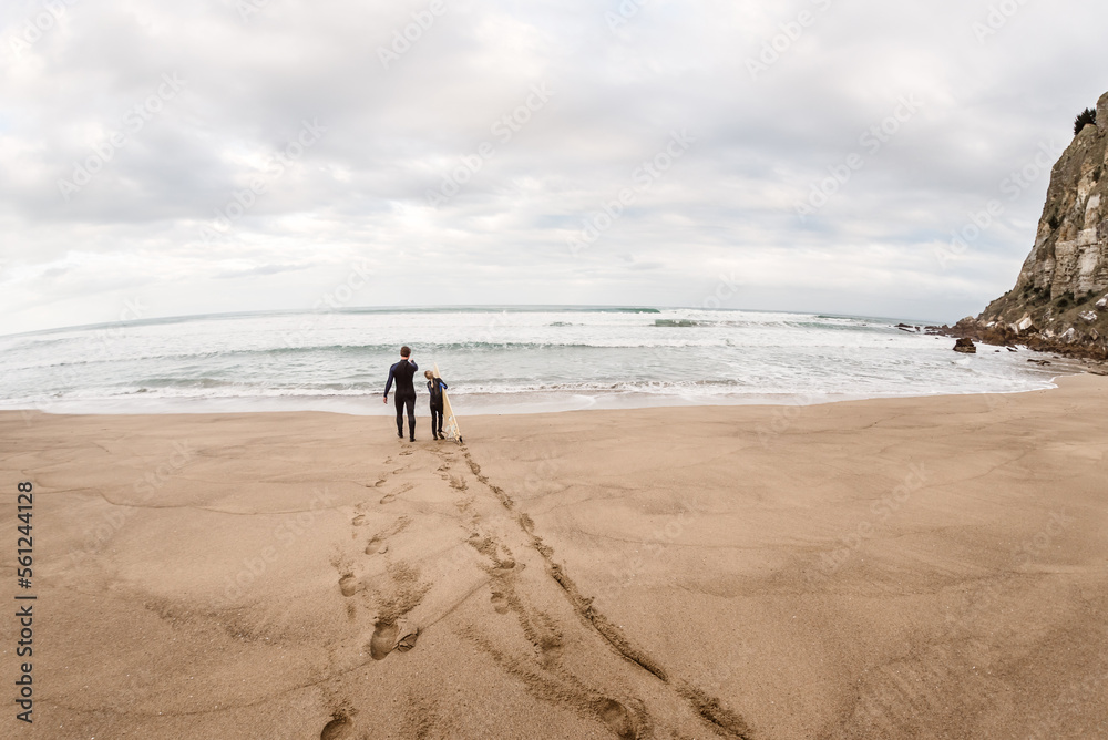 Man and girl walking to ocean with surfboard Man and girl walking to ocean with surfboard