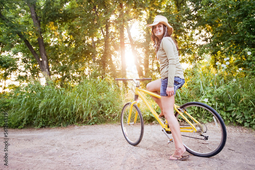 a young woman stops looking back on a yellow bike. photo