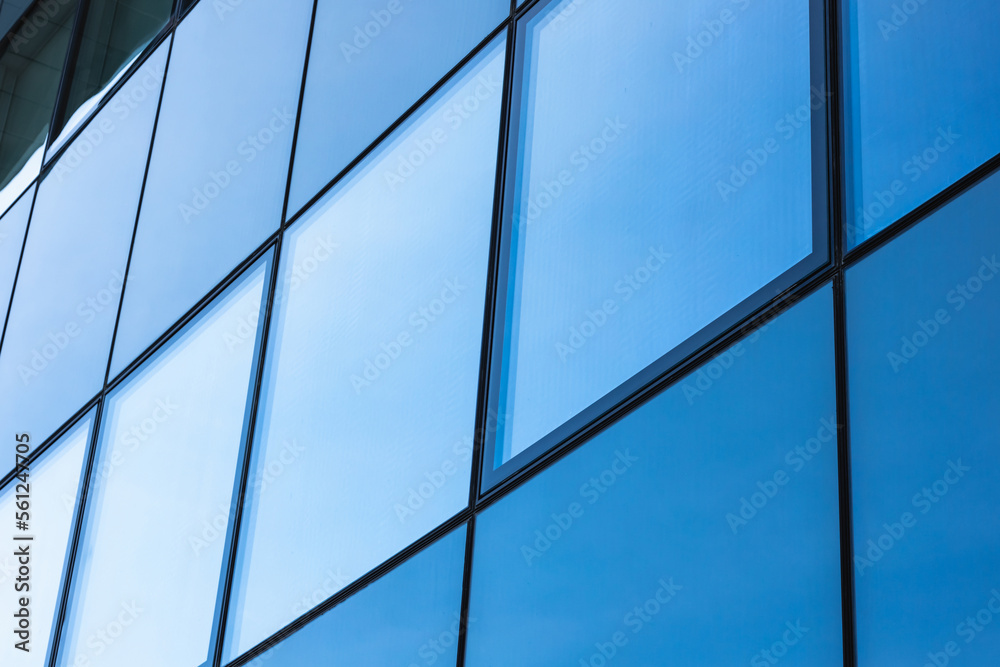 The blue sky is reflected in the windows of a modern office building. Architecture and exterior of contemporary houses The blue sky is reflected in the windows of a modern office building. Architecture and exterior of contemporary houses