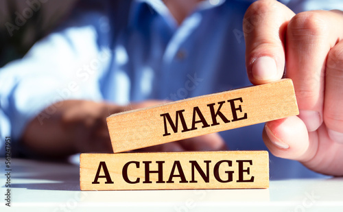 Closeup on businessman holding a wooden block with "MAKE A CHANGE", Business concept