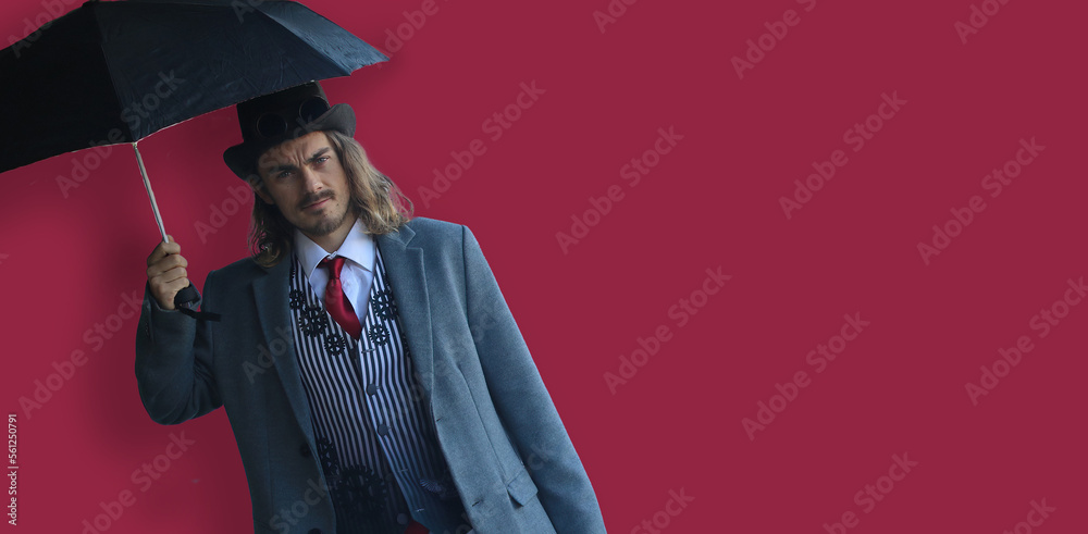 Handsome man with umbrella in a suit, on crimson red background