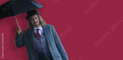 Obraz na płótnie Handsome man with umbrella in a suit, on crimson red background w salonie