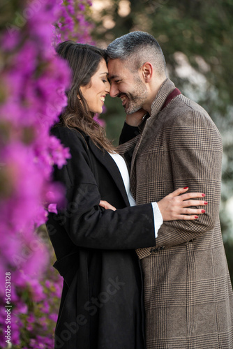 Couple in love very close together next to some violet flowers © Marc Calleja