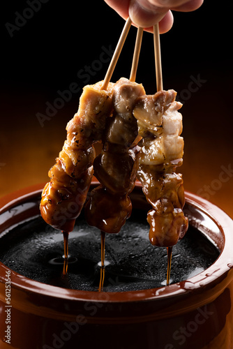 Tableau sur toile 鶏のモモ肉の串焼きをタレ壺の中の焼き鳥のタレに漬ける