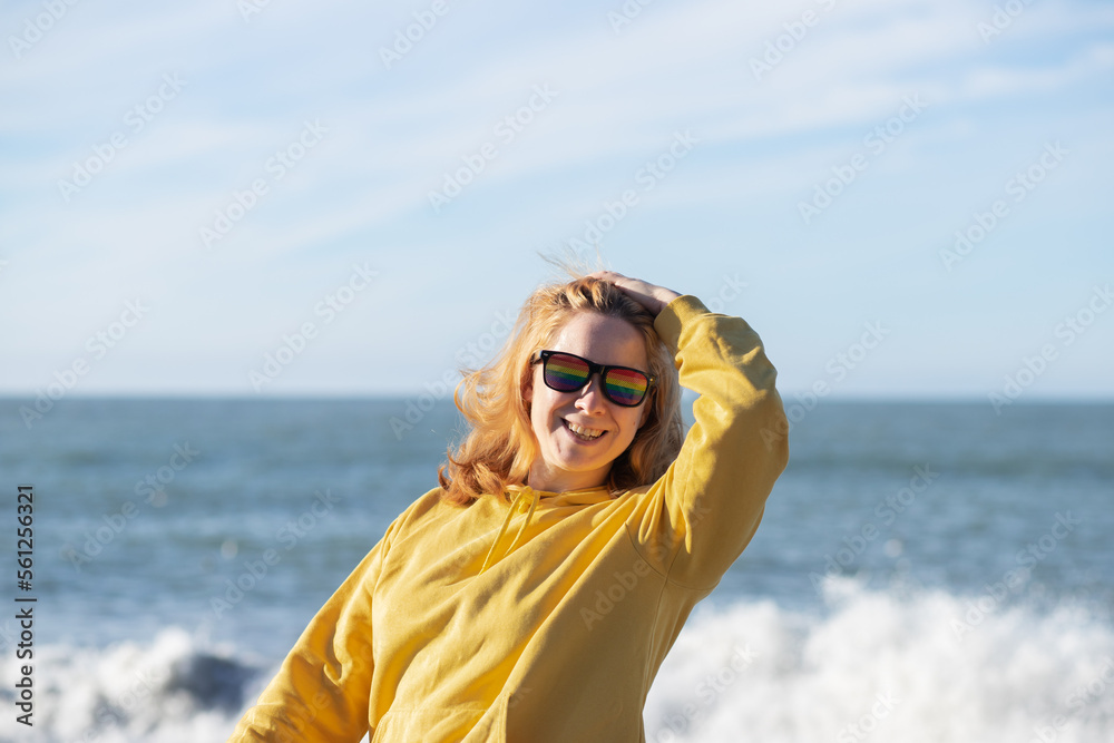 lesbian woman in rainbow glasses laughing and smiling on the beach