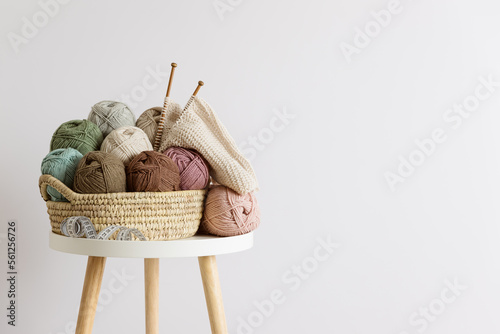 Natural wool in balls of various pastel colors in a wicker basket on table.
