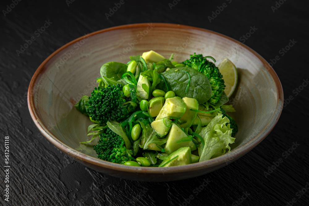 Green Salad from avocado, beans, broccoli in a ceramic plate on a dark textured background. Restaurant menu Isolated on black Green Salad from avocado, beans, broccoli in a ceramic plate on a dark textured background. Restaurant menu Isolated on black