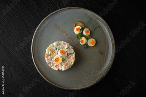 Olivier in a ceramic plate on a dark textured background. Restaurant menu Isolated on black