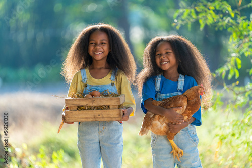 Two young black girls carrying chickens and holding eggs, rural happy lifestyle Fototapet