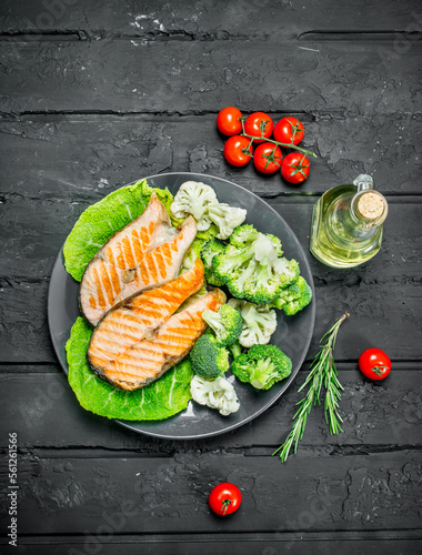 Grilled salmon steaks with tomatoes and broccoli in a plate.