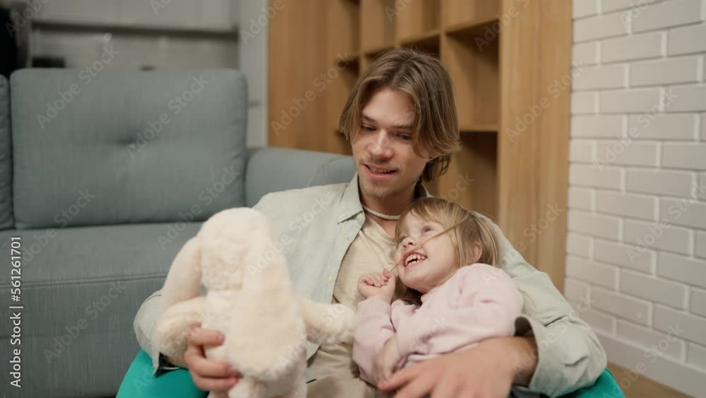 Father and daughter play together with soft toy, sitting on the chair Father and daughter play together with soft toy, sitting on the chair