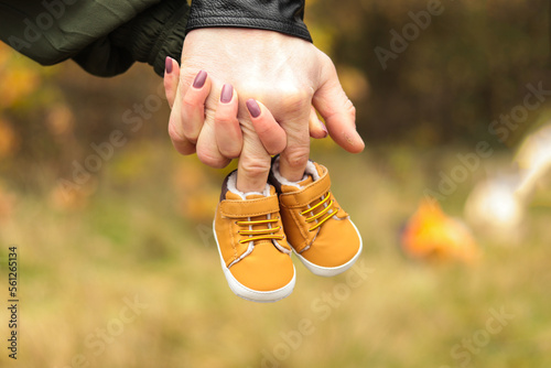 Woman and man holding hands and their unborned the first baby's shoes  photo
