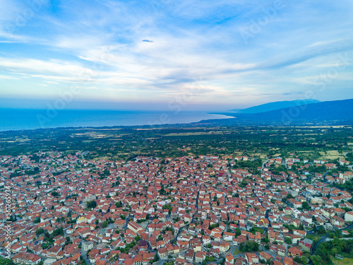 Greek town of Litochoro with small houses and green vegetation against the backdrop of the Aegean Sea and a cloudy sky