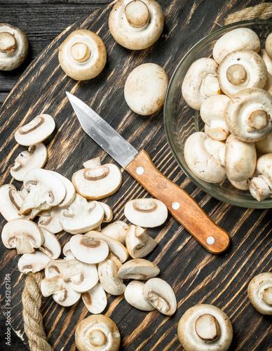 Pieces of fresh mushrooms on a tray with a knife.