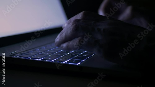 close up of a person typing on a laptop in dark environment