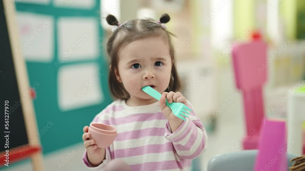Adorable chinese toddler sucking fork toy at kindergarten Adorable chinese toddler sucking fork toy at kindergarten