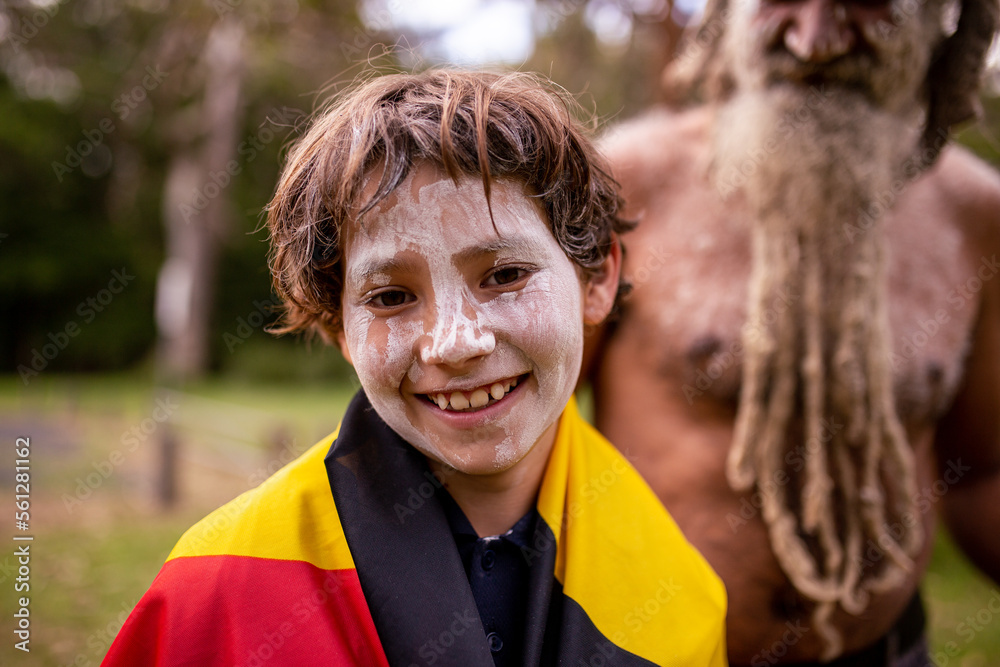 Smiling young Aboriginal boy wearing the Aboriginal flag and white face