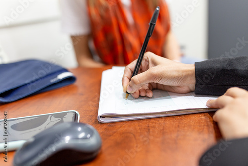 Close-up of doctor's hand writing a prescription for her patient photo