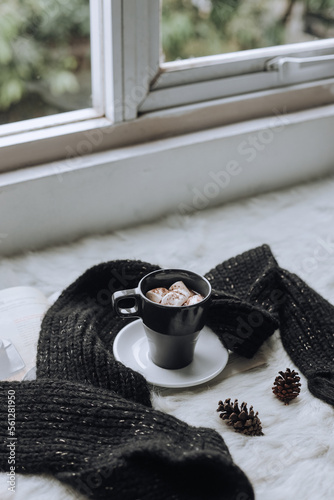 A cup of hot chocolate with marsmallow arrange with knitted warm winter scarf  photo