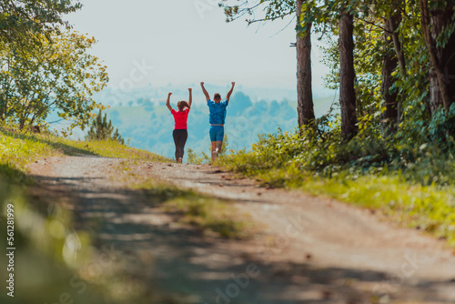 Couple enjoying in a healthy lifestyle while jogging on a country road through the beautiful sunny forest, exercise and fitness concept