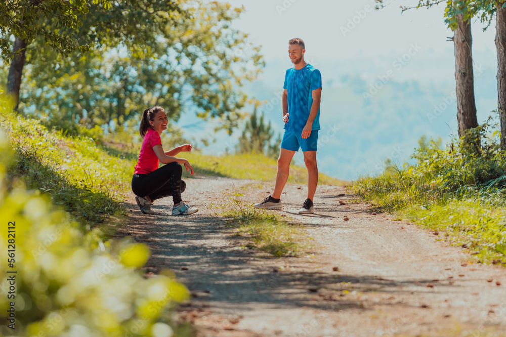 Obraz premium A young couple resting after an exhausting run in the early morning on an idyllic forest road