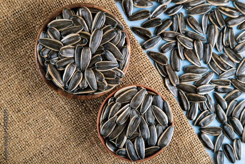 Black sunflower seeds in a bowl on burlap sack,top view