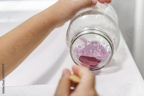 Chemical experiment on growing crystals. Child hands take out grown crystal from a jar. Steps by step photos.