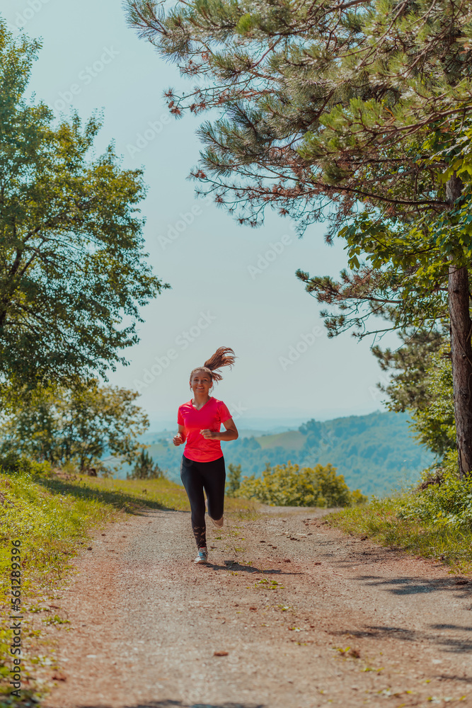 Young happy woman enjoying in a healthy lifestyle while jogging on a country road through the beautiful sunny forest, exercise and fitness concept Young happy woman enjoying in a healthy lifestyle while jogging on a country road through the beautiful sunny forest, exercise and fitness concept