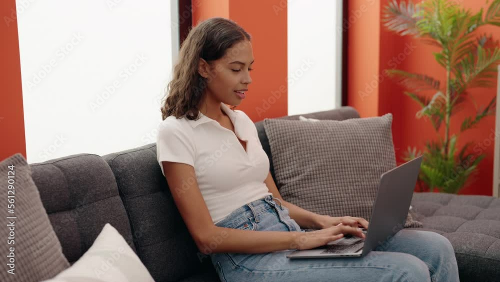 Young african american woman using laptop sitting on sofa at home Young african american woman using laptop sitting on sofa at home