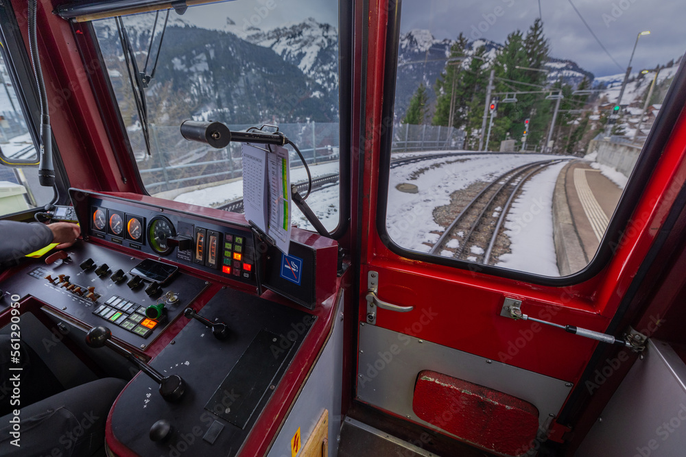 Inside of the drivers cab of older style EMU of a narrow gauge railway from Lauterbrunnen to Jungfraujoch in winter time. Visible commands and rails in the front.