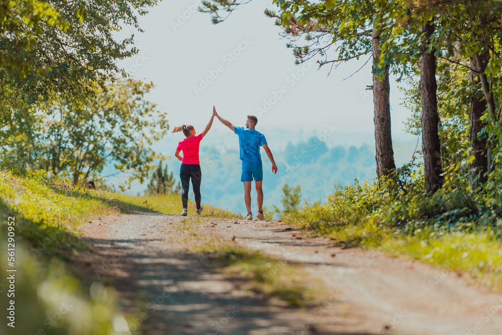 Couple enjoying in a healthy lifestyle while jogging on a country road through the beautiful sunny forest, exercise and fitness concept Couple enjoying in a healthy lifestyle while jogging on a country road through the beautiful sunny forest, exercise and fitness concept