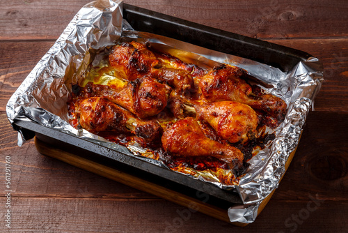 Chicken legs baked in sauce and spices with a crispy crust on a baking sheet.