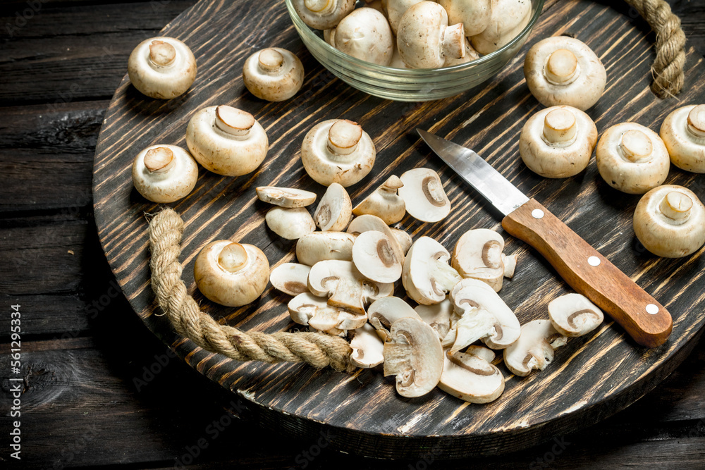 Fototapeta premium Mushrooms in a bowl and pieces of mushrooms on a tray with a knife.