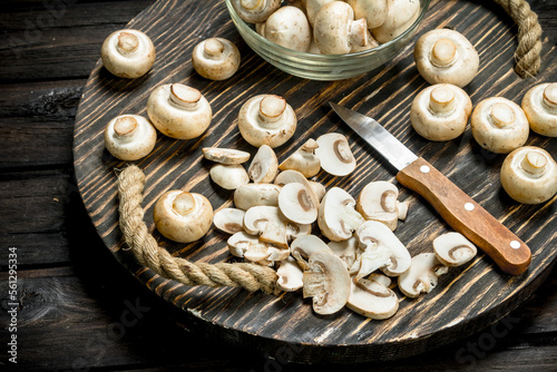 Mushrooms in a bowl and pieces of mushrooms on a tray with a knife.