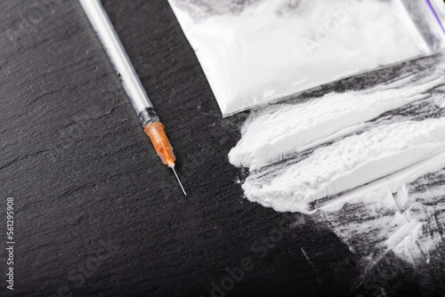 Cocaine or other illegal drugs, white powder, money, pills, syringe on black background.