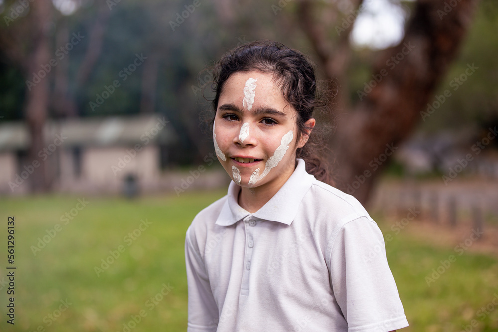 Young Aboriginal girl wearing white face paint smiling at the camera Young Aboriginal girl wearing white face paint smiling at the camera