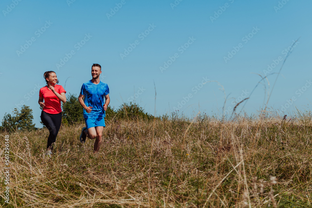 Couple enjoying in a healthy lifestyle while jogging on a country road through the beautiful sunny forest, exercise and fitness concept