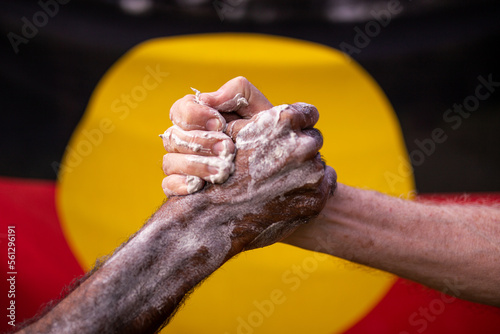 Reconciliation concept - indigenous hand clasped in front of aboriginal flag