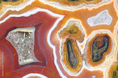 A cross section of the agate stone with quartz geode. Multicolored silica bands colored with metal oxides are visible. Macro photography of the surface of the cut. Origin: Atlas mountains, Morocco.
