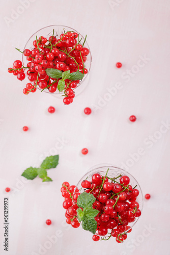 Fresh red currants in crystal glasses on a pink background