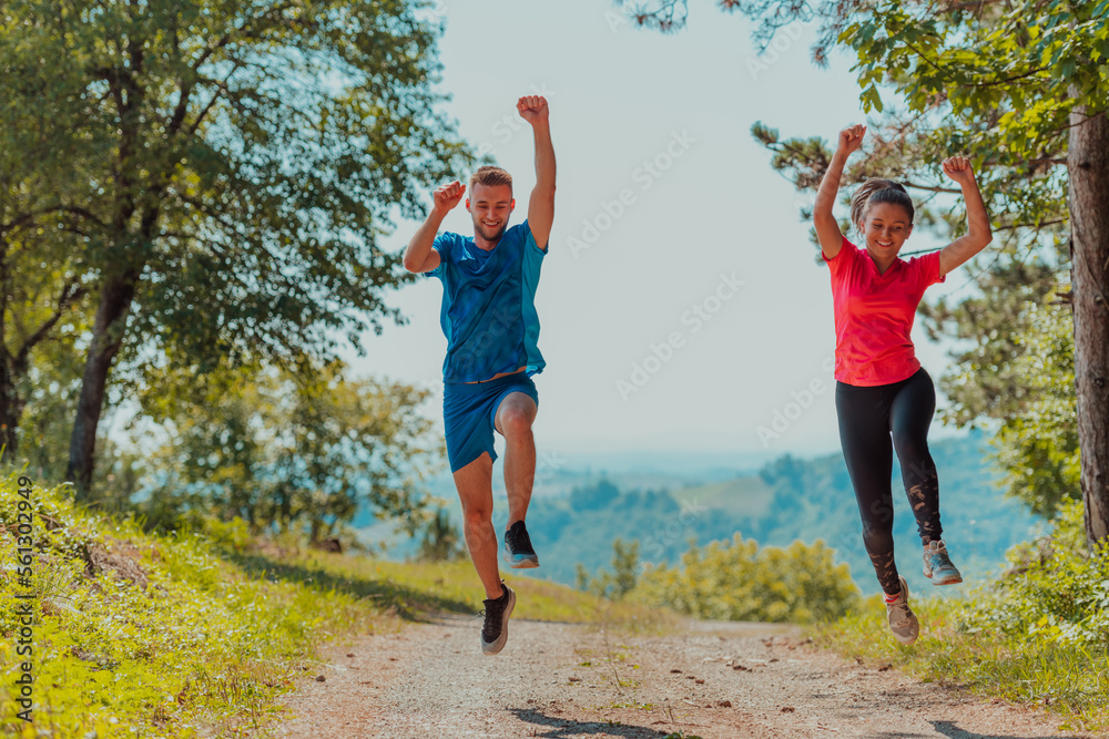 Obraz premium Couple enjoying in a healthy lifestyle while jogging on a country road through the beautiful sunny forest, exercise and fitness concept