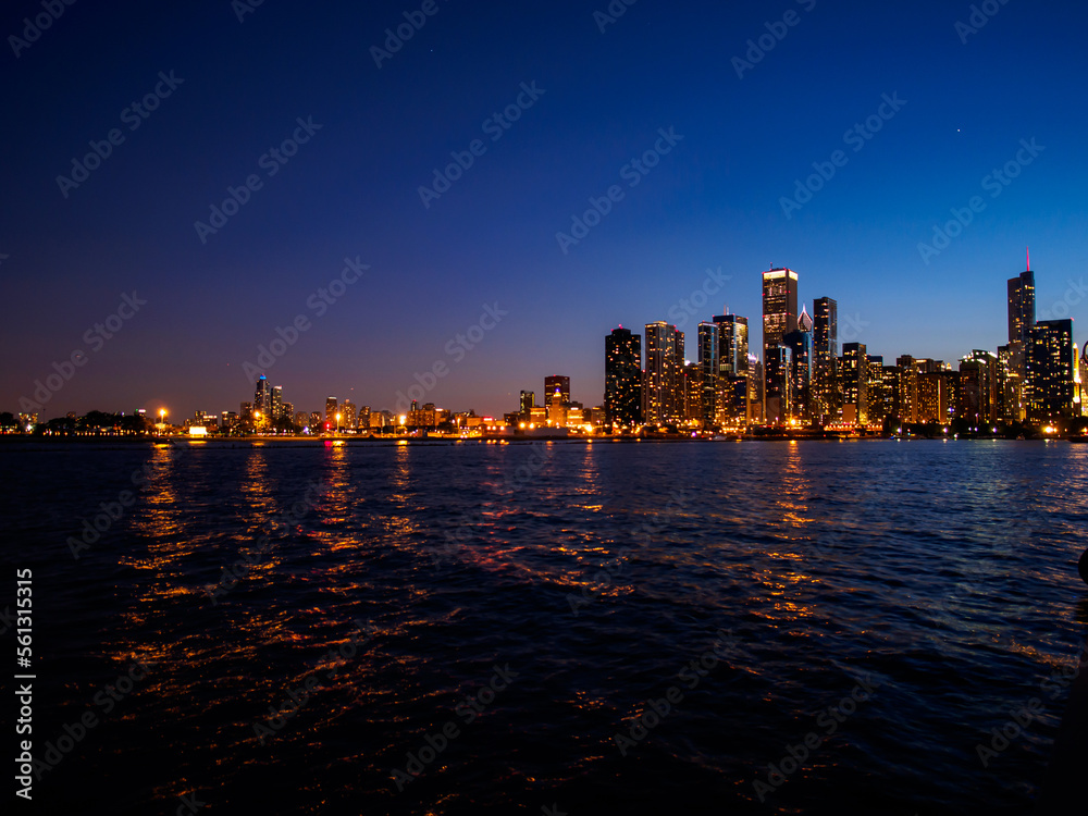 Chicago skyline with lights at night with water and clear sky.