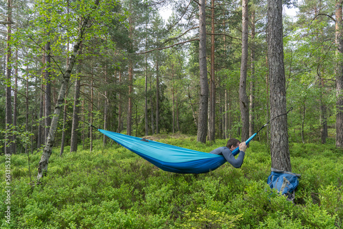 Hiker sleeping in a hammock between trees.