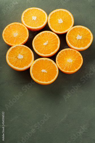 Halves of oranges in the shape of a flower. Juicy oranges on a green background. Top view. Copy space