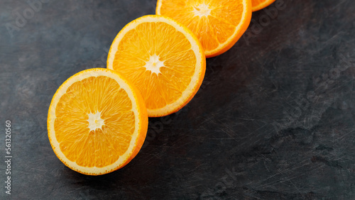Halves of ripe oranges on a dark background. Sliced oranges for breakfast. Copy space
