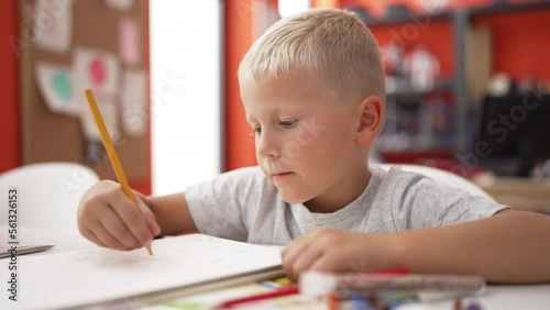 Wallpaper Mural Adorable toddler student drawing on notebook sitting on table at classroom Torontodigital.ca