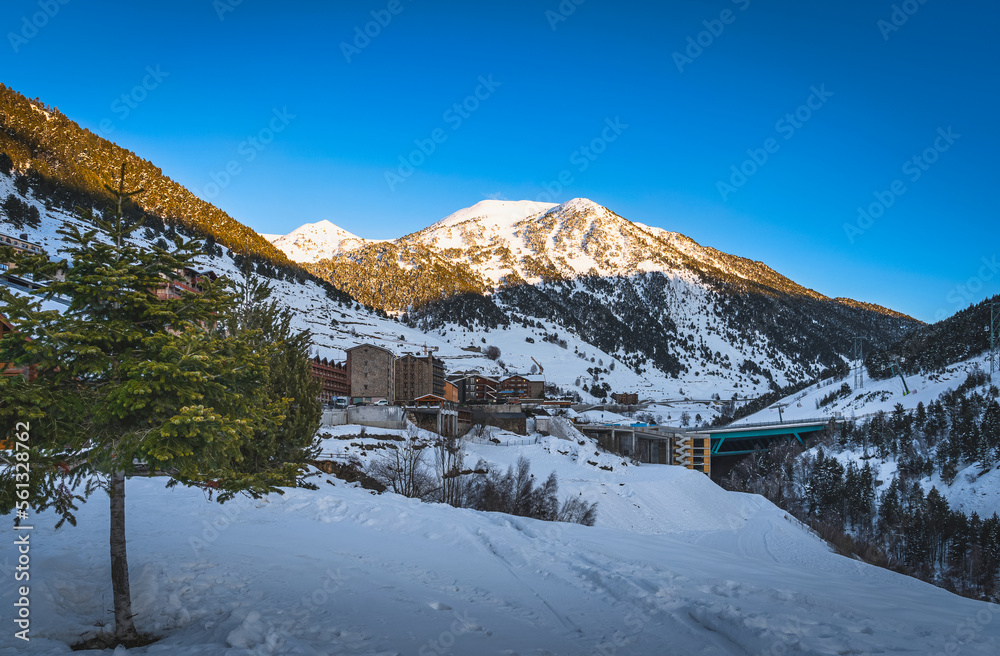 Soldeu village with mountain range illuminated by sunset in the background. Ski winter holidays in Andorra, Grandvalira, Pyrenees Mountains