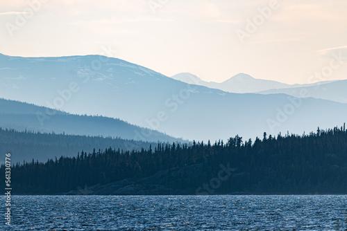 Summertime Canadian views with a lake, mountains in the distance and boreal forest. Moody, dark scene. 