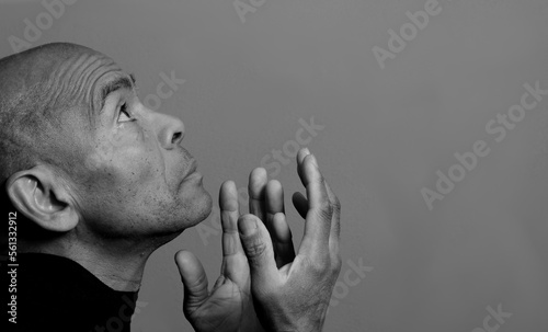 man praying to god with hands together with black grey background with people stock photo 